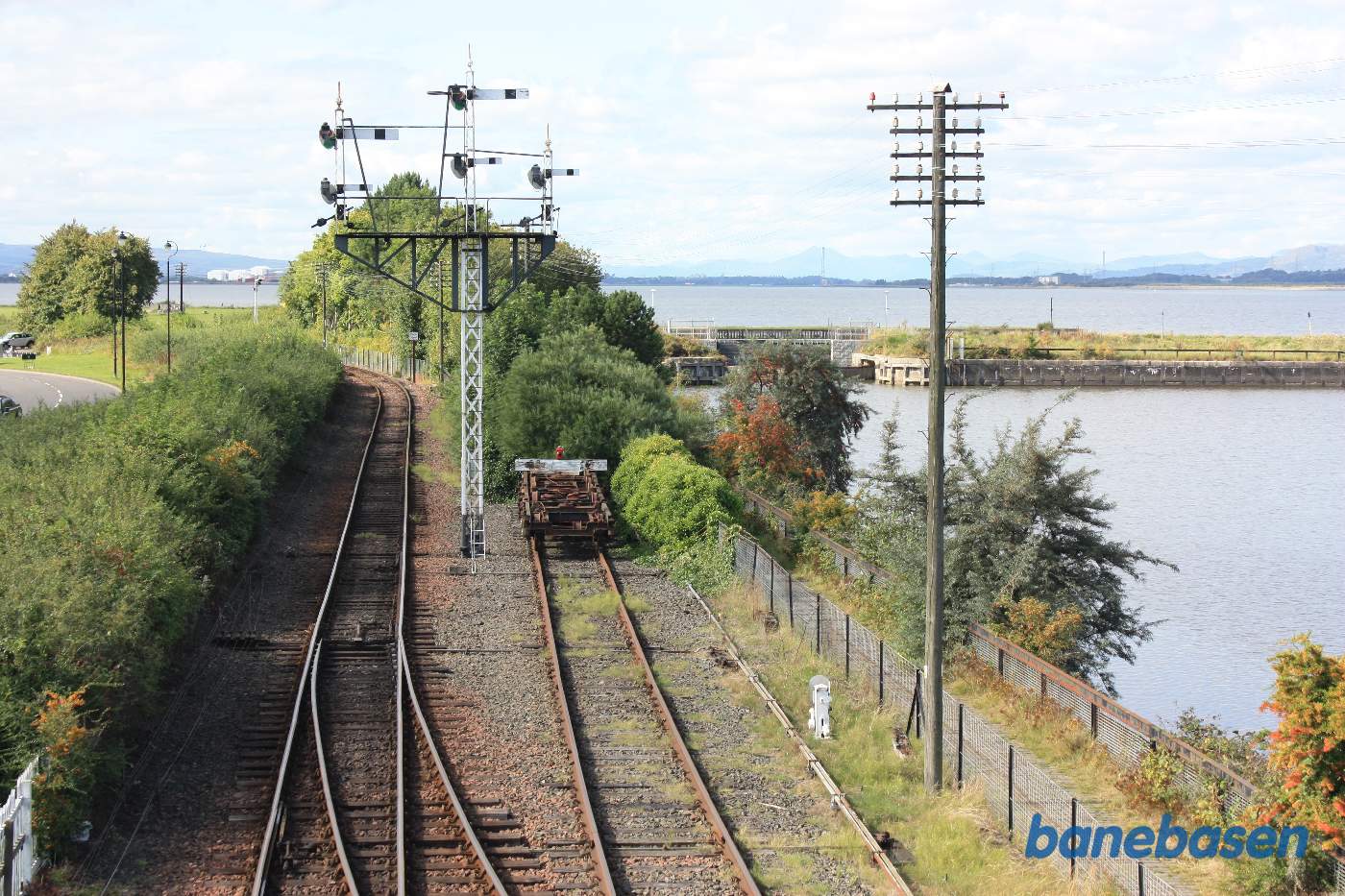 Fra gangbroen over banen får man et godt billede af banen ud af stationen mod Manuel samt havnen til højre med slusen og fjorden ind fra Nordsøen