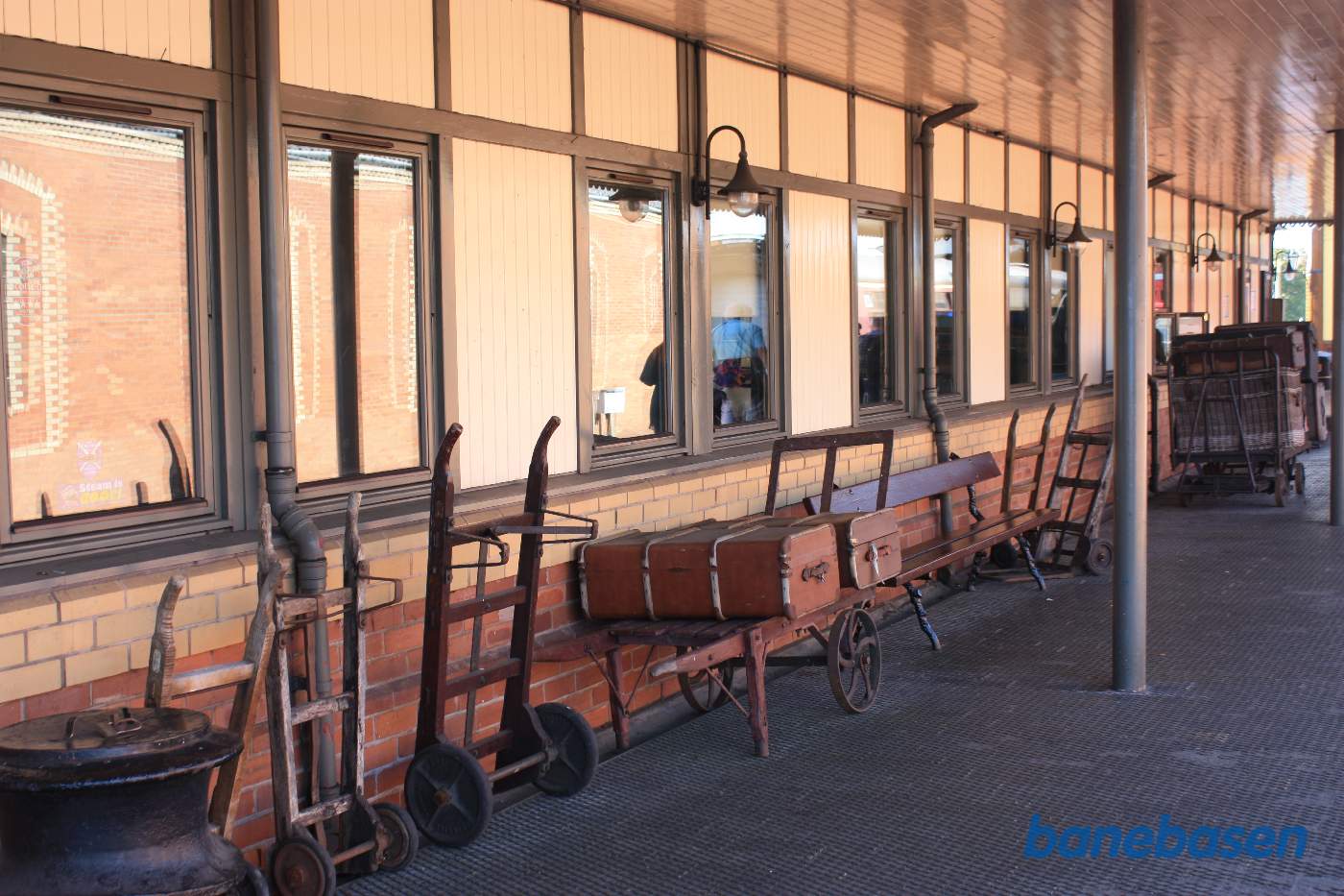 Langs stationsvæggen er på perronen udstillet kufferter og sækkevogne