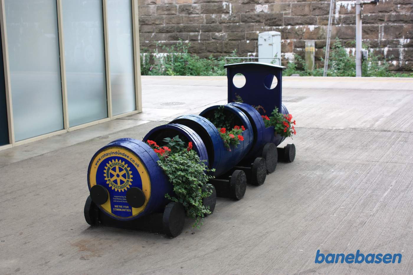 På perronen er udstillet et lille blomster tog med reklame for Rotery