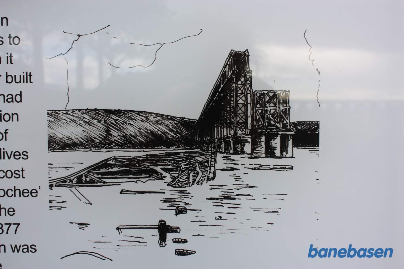 En mindetavle viser her et billede af den høje smalle bro, der ikke kunne modstå en kraftig vestenvind, og derfor væltede