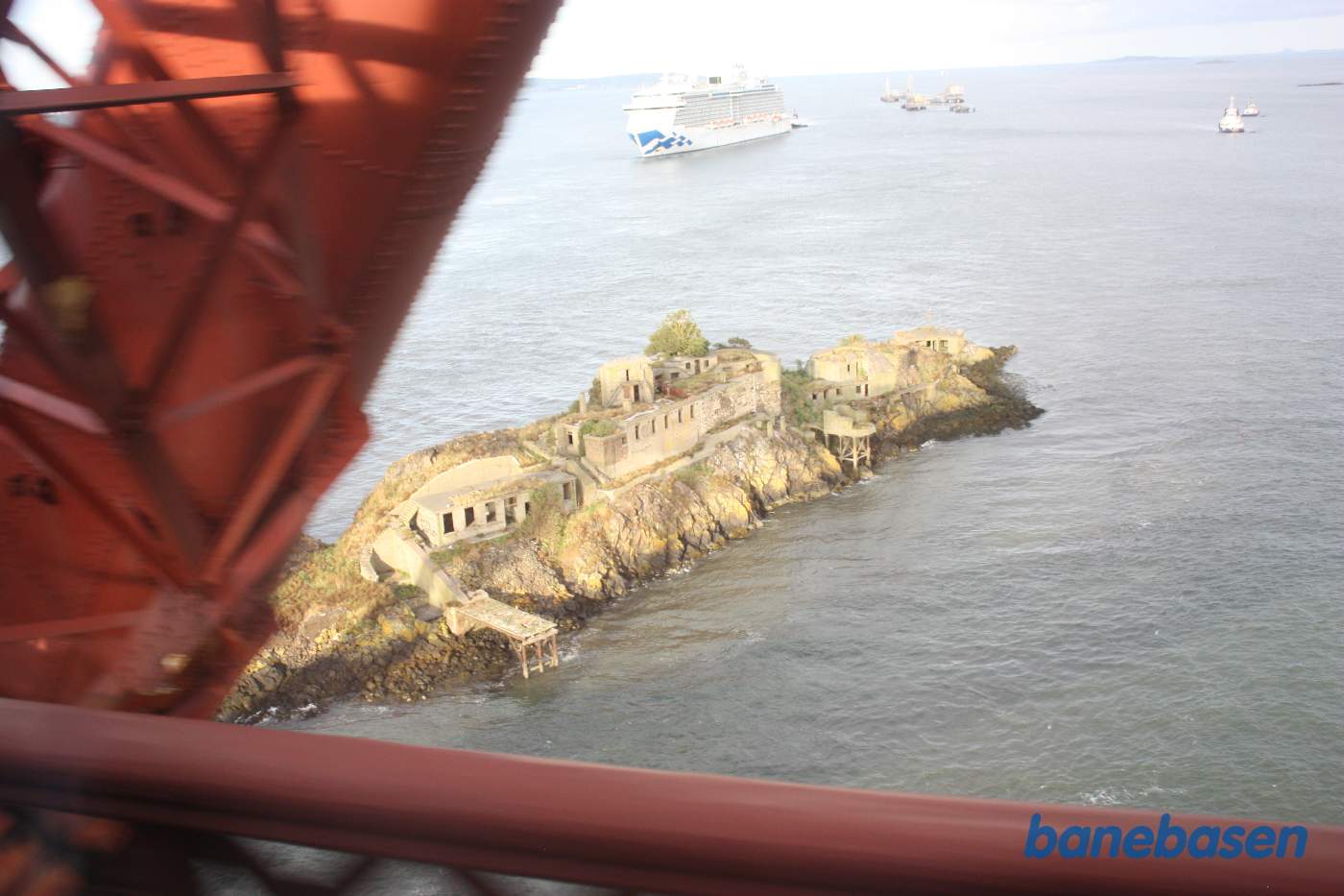 Et skud ud af togvinduet af den lille ø med Inch Garvie Castle og et stort krydstogtskib og Nordsøen i baggrunden