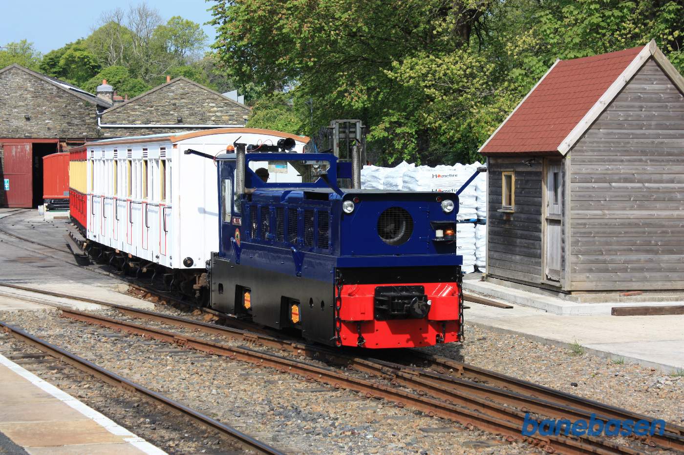 Et blåt diesellokomotiv flytter vogne fra et spor til et andet