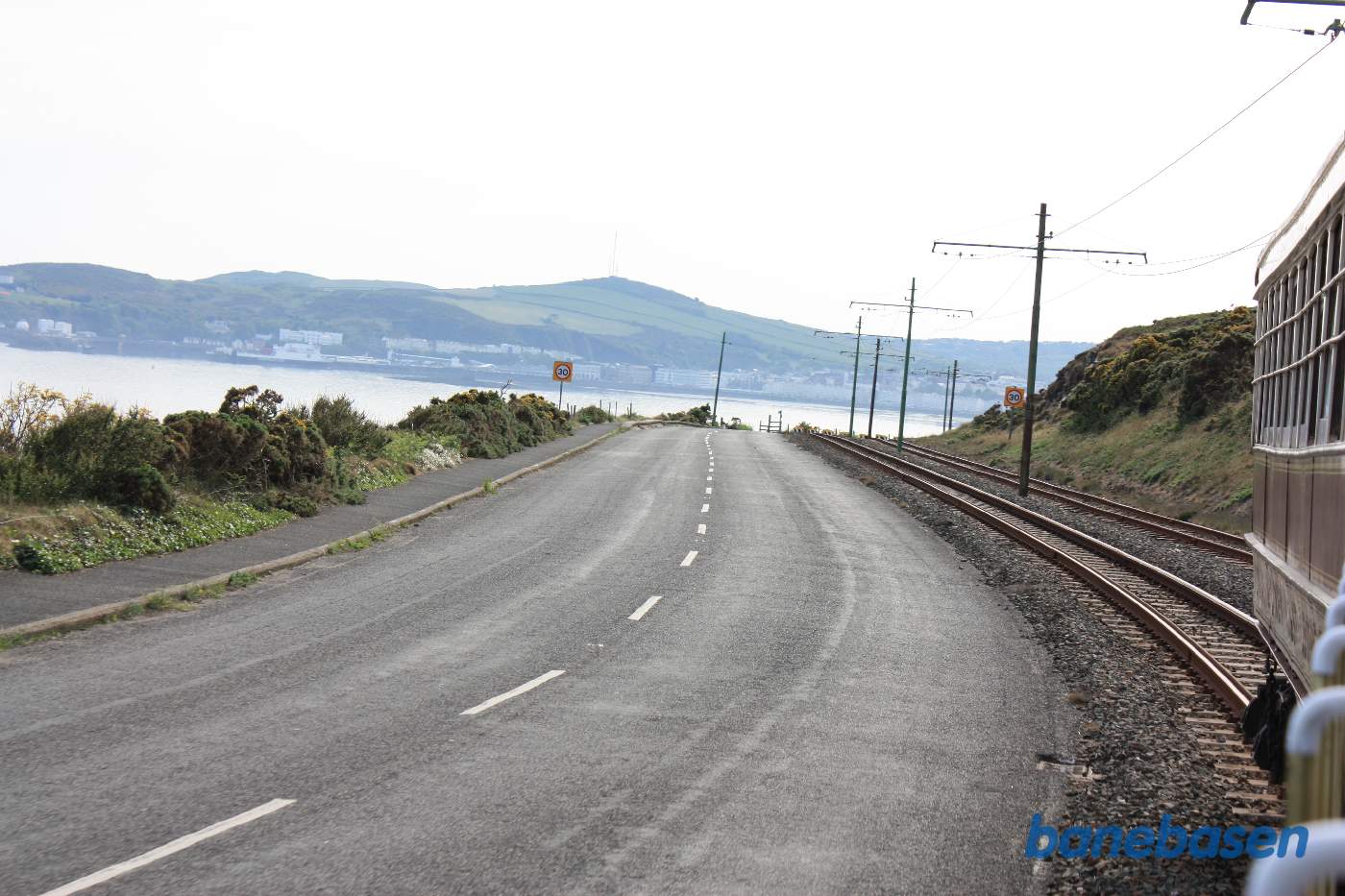 Sporvognen er på vej ud af Douglas. Det første stykke vej løber vejen og banen langs kysten