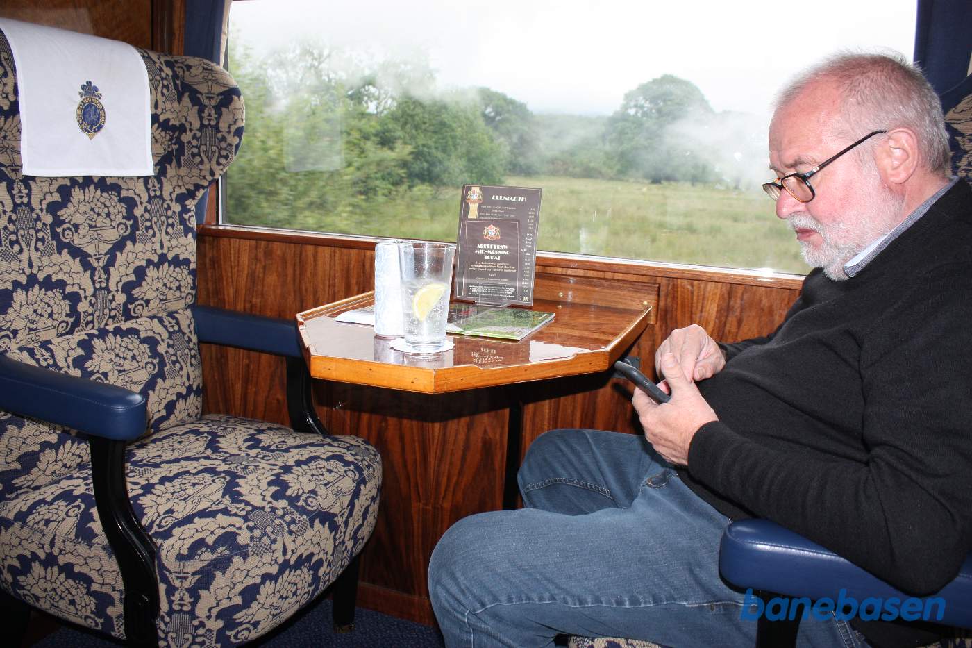 Gin og Tonic og så tjek af mobiltelefonen. Bemærk det hvide beskyttelsesklæde med det flotte broderi