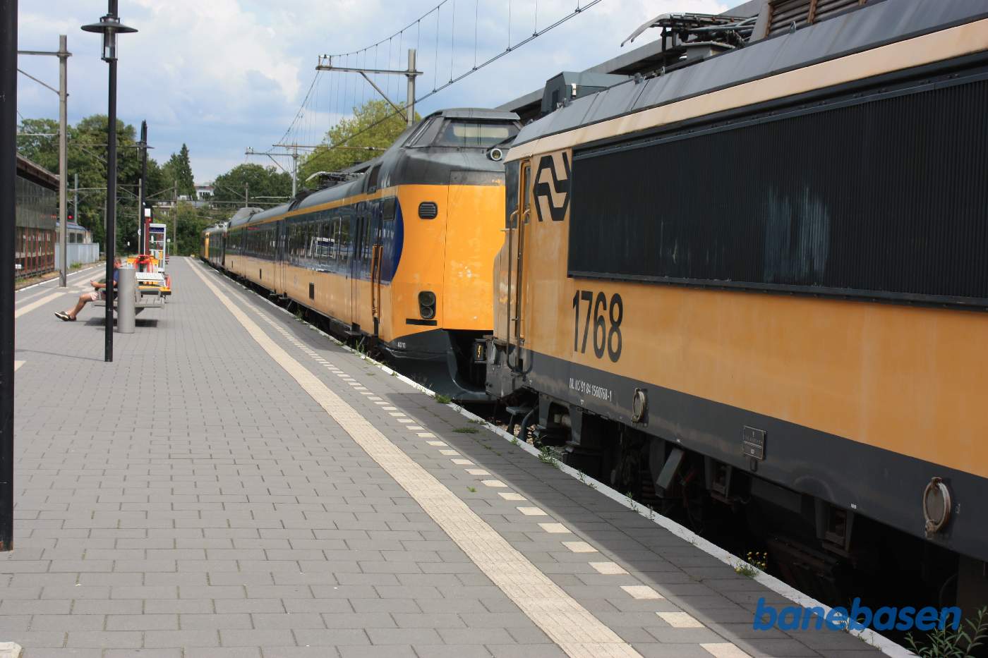 Persontog ved perron samt et elektrisk lokomotiv