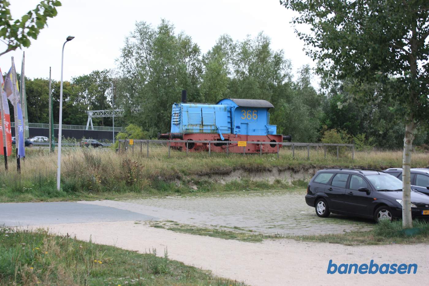Det lille tog passerer ved indkørslen til parkeringspladsen et udstillingslokomotiv, der skal tiltrække kunderne