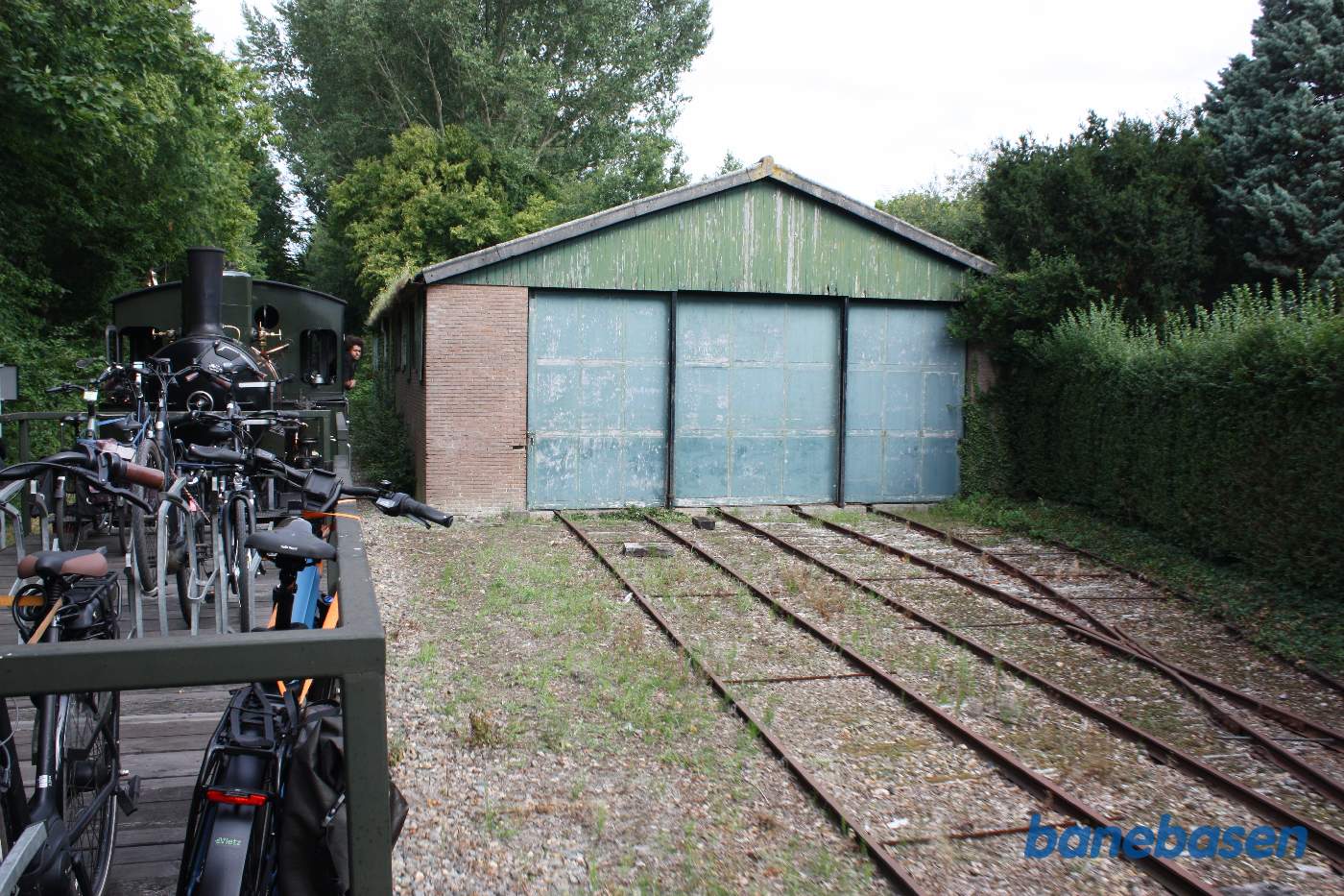 Toget passerer en lille vognhal på stationen