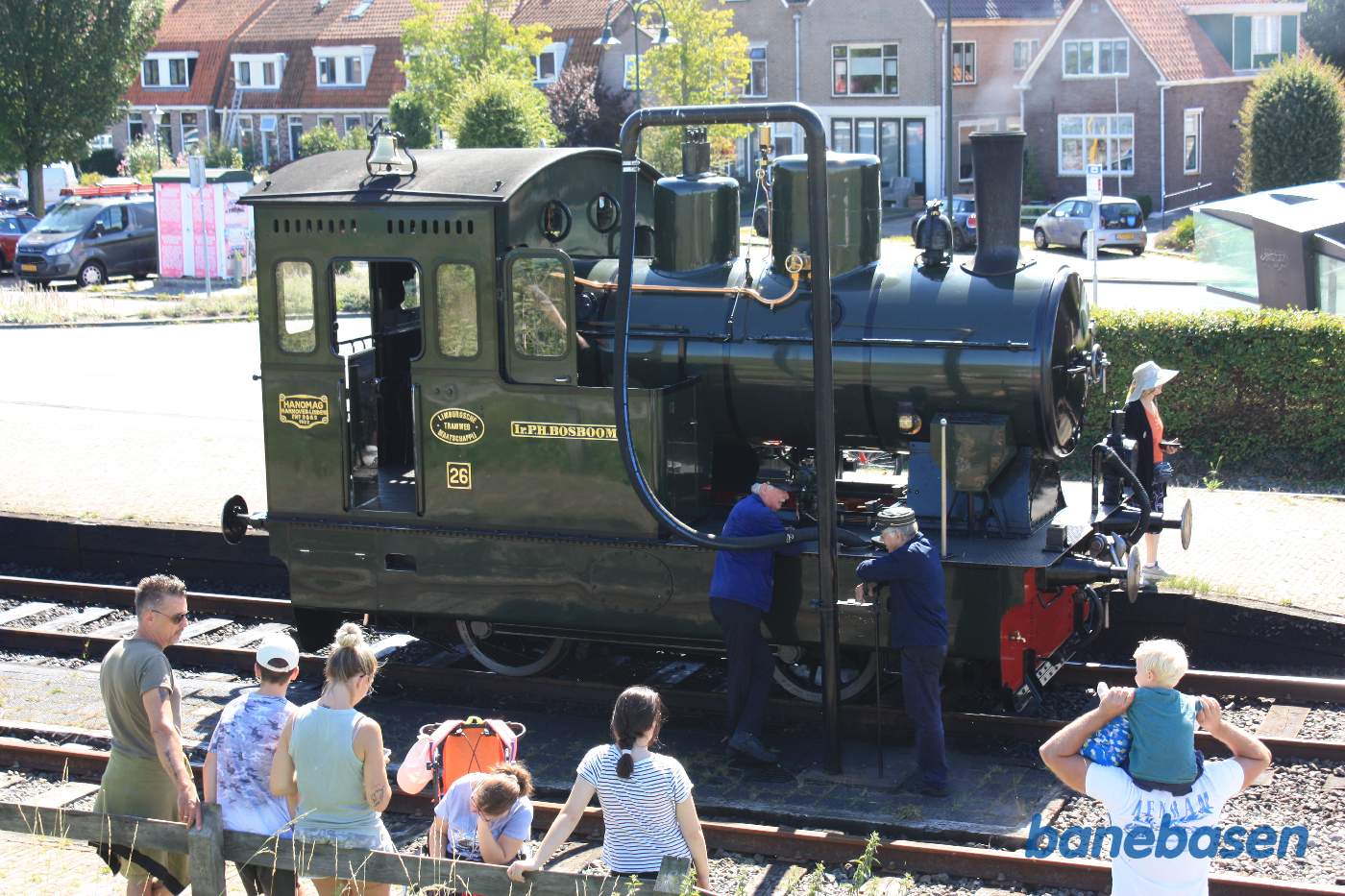 Der fyldes vand på lokomotivet i dets bundtank mens gæsterne ser på