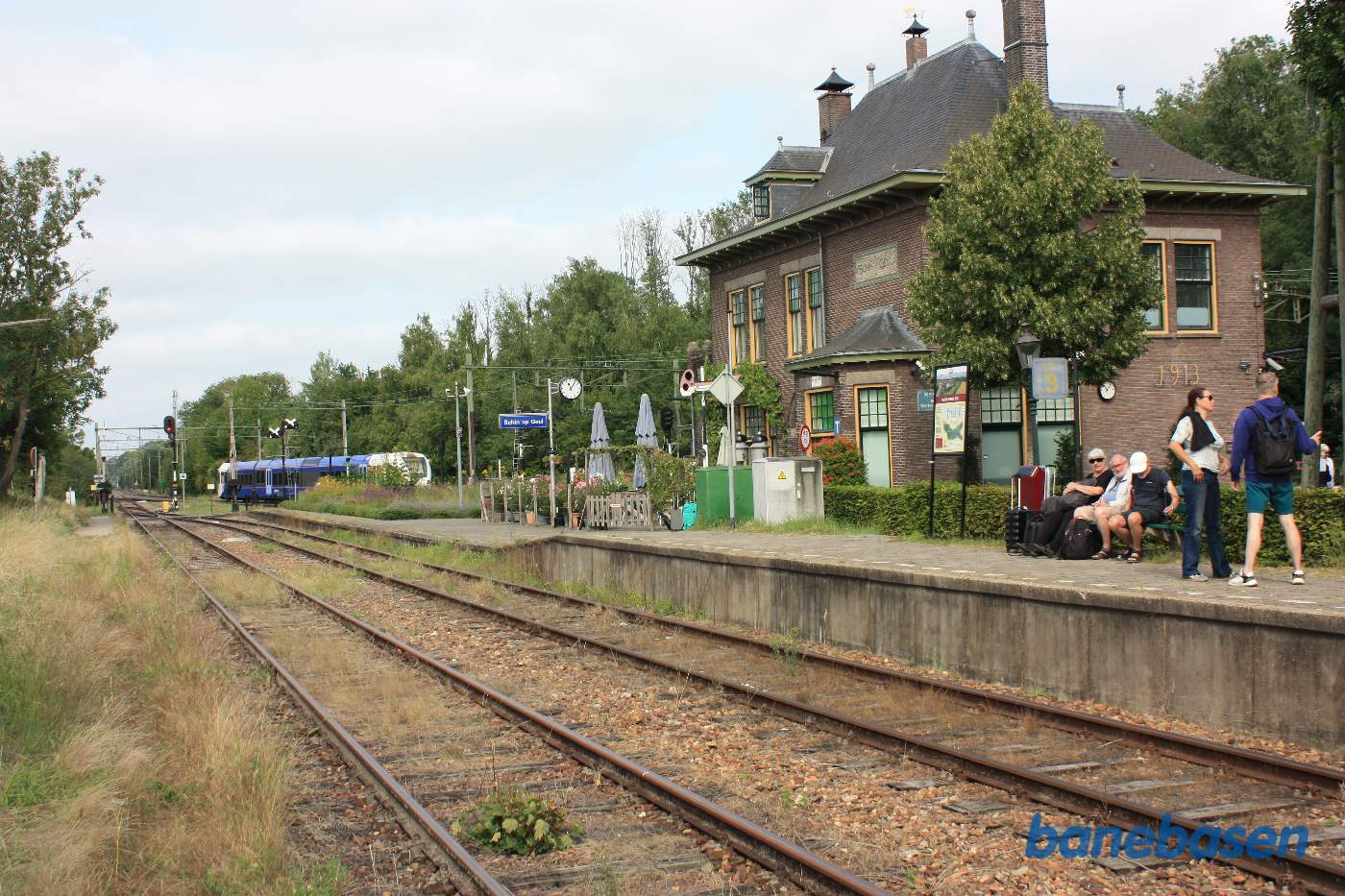 Stationsbygningen set fra veteranbanens perron. Tog til Maastricht på vej ud af stationen
