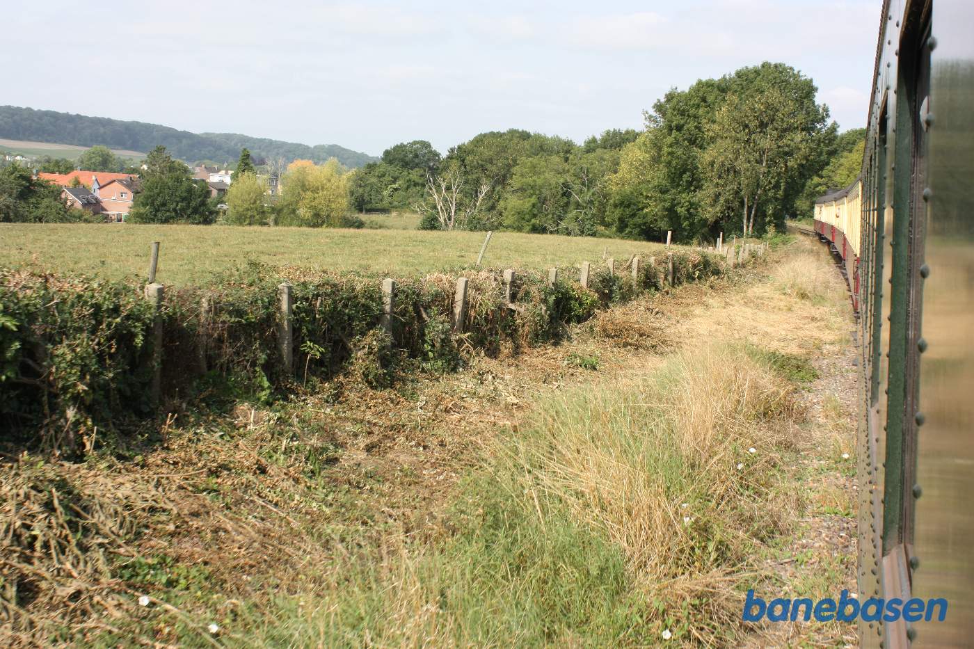 Billede ned langs toget, bagud. Marker og hegn langs banen