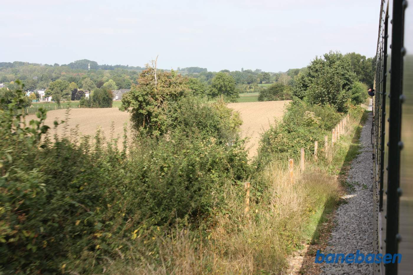 Billede ned langs toget, bagud. Marker og hegn langs banen
