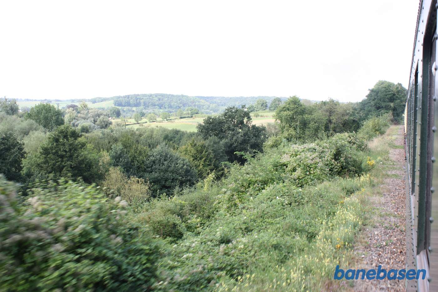 Billede ned langs toget, bagud. Marker og skov langs banen