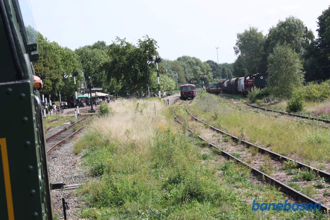 Toget nærmer sig perronen. Rød skinnebus til højre, midt i billedet