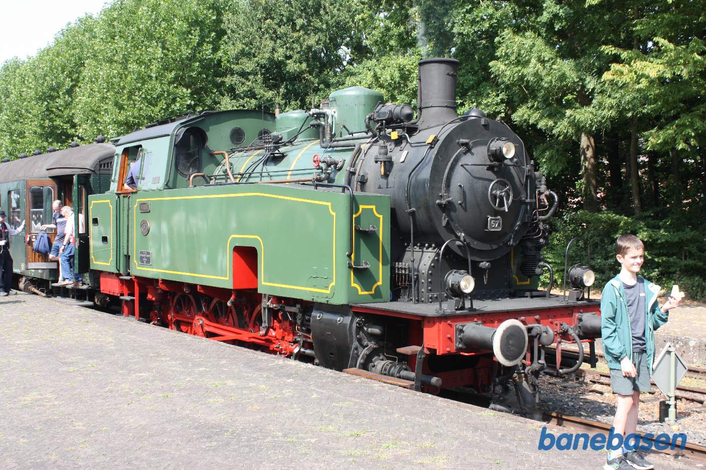 Damptoget ankommet til stationen. Folk stiger ud og en dreng fotograferes foran lokomotivet