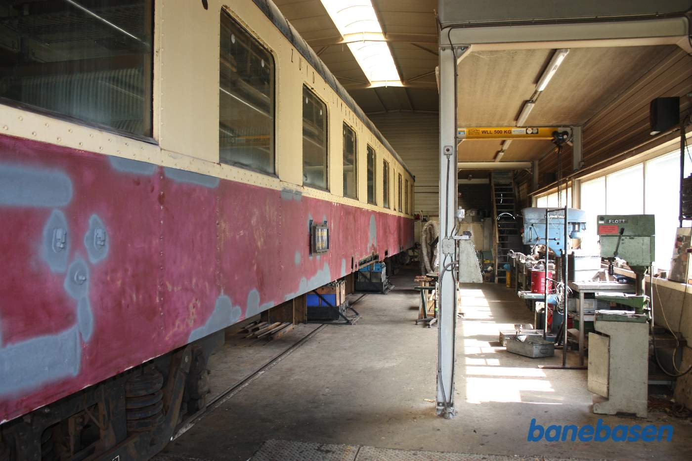 En rød-beige personvogn i værkstedet