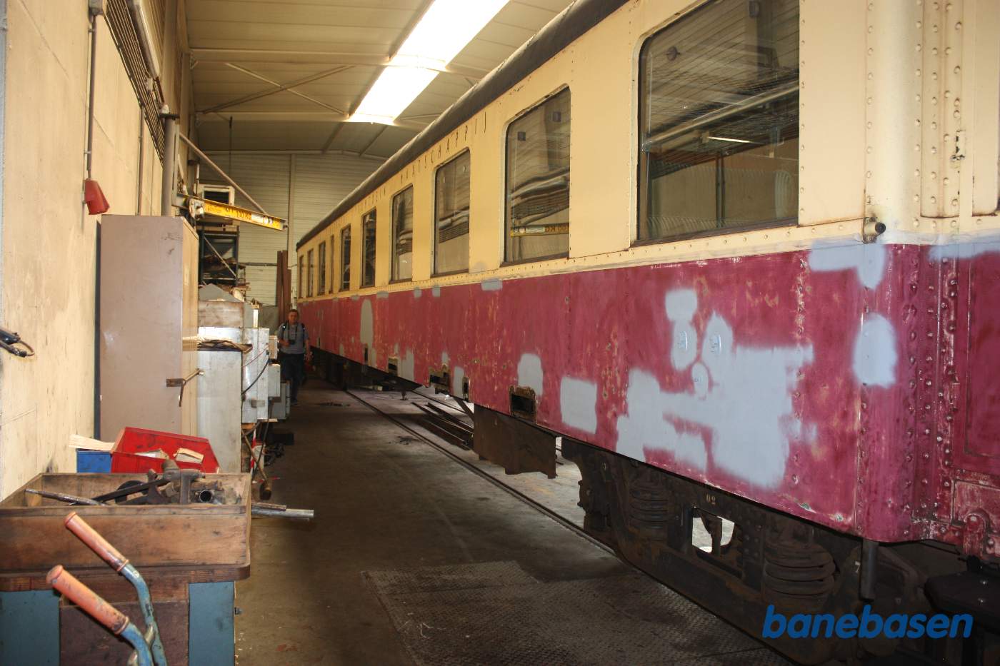 En rød-beige personvogn i værkstedet