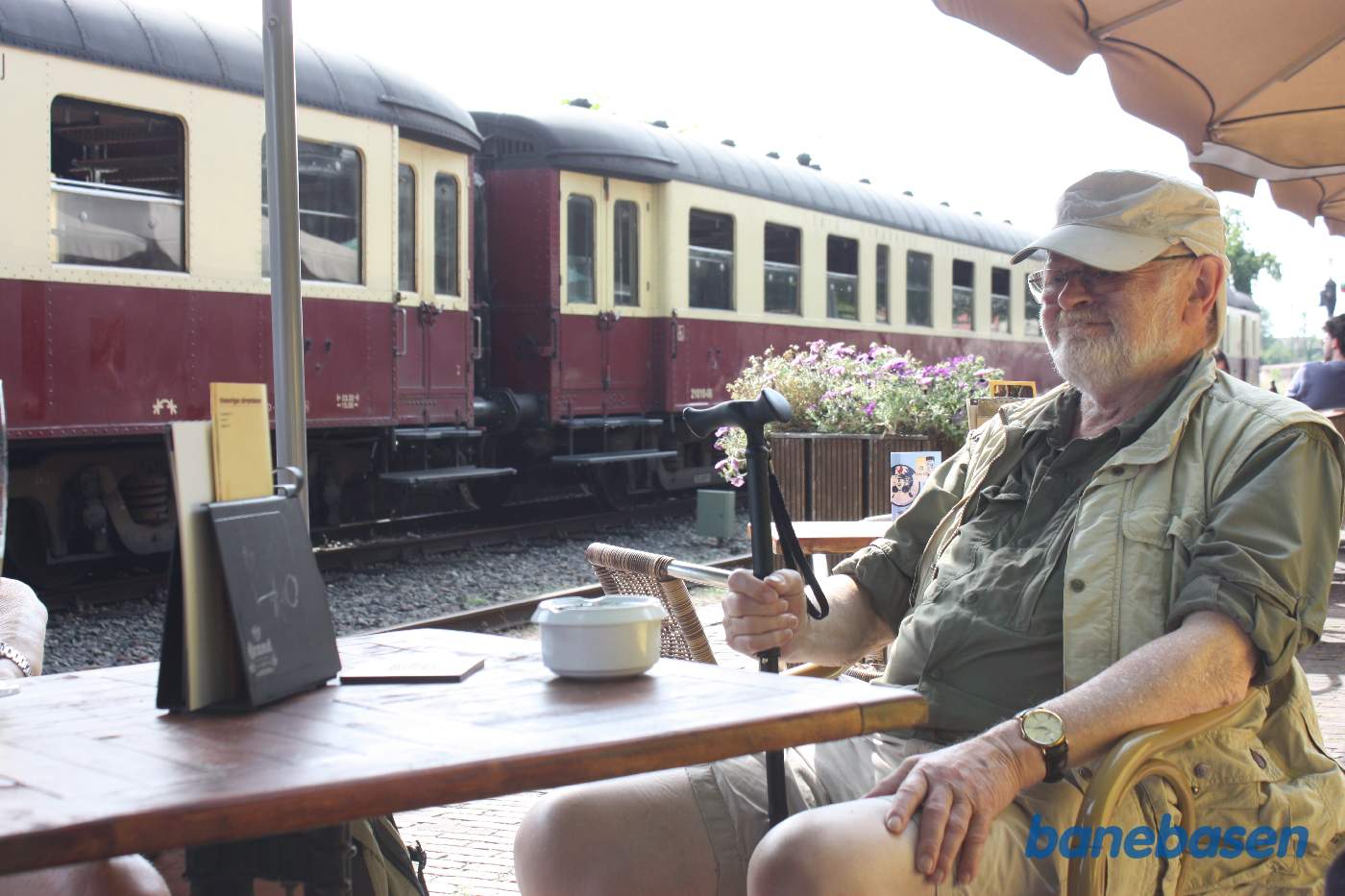 En gæst på Jernbanerestauranten nyder det gode vejr og udsigten til veterantoget