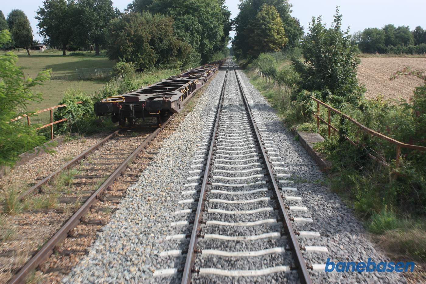 En meget lang række containerbærevogne er hensat i det andet spor