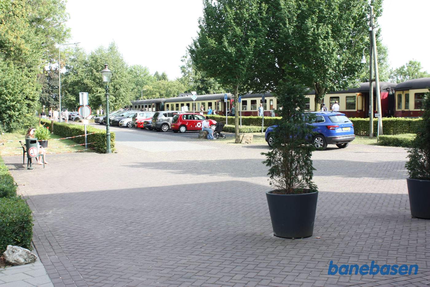 Persontoget ankommer til stationen, set fra vejen og stationens parkeringsplads