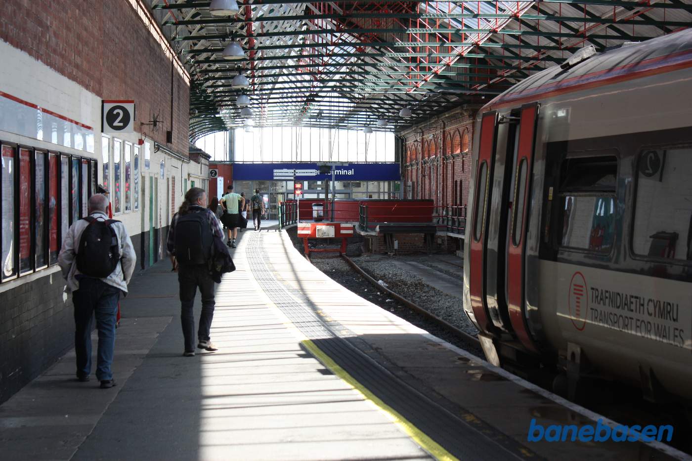 Perronsporet inde i hallen. Nede for enden, indgangen til den nye stations forhal med billetsalg, forretning med mad og drikke mv.